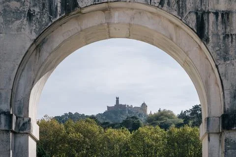 Pena Palace on hill framed by ancient stone arch in Sintra, Portugal Stock Photos