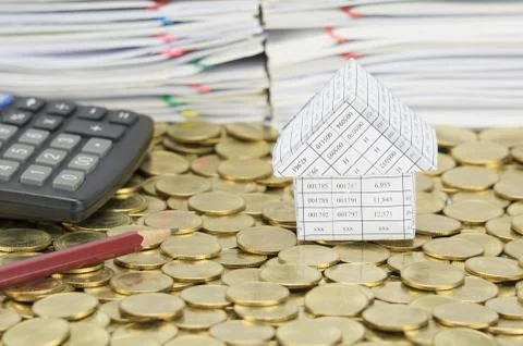 Pencil and calculator with house on stack of gold coins Stock Photos
