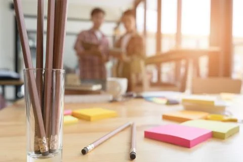 Pencil and sticky note on table with background of young university student.. Stock Photos