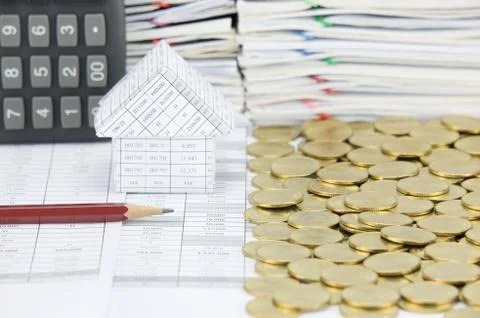 Pencil in front of house with stack of gold coins Stock Photos
