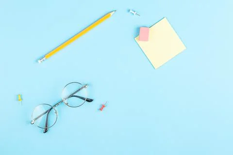 Pencil glasses pin note sheet on blue background. Stock Photos