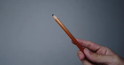 Pencil held by the hand of a young man showing it to the camera inside a room Stock Footage 296304654