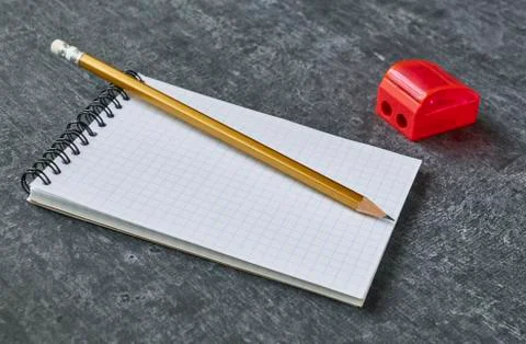 Pencil lies on the notebook next to the sharpener, gray background, shallow d Stock Photos