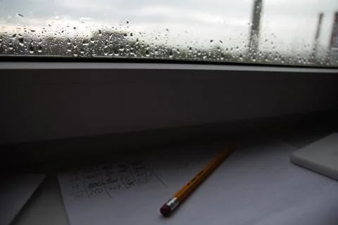 Pencil lying on scribbled paper on the windowsill on a rainy day. on the glas Stock Photos