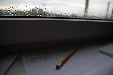 Pencil lying on scribbled paper on the windowsill on a rainy day. on the glas Foto stock