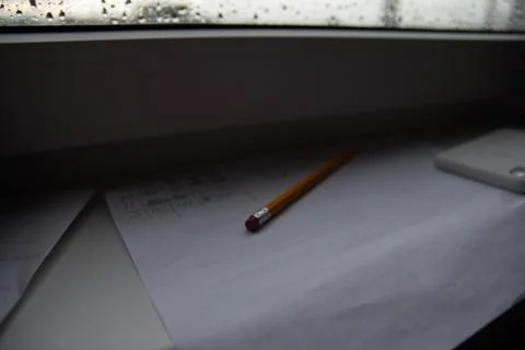 Pencil lying on scribbled paper on the windowsill on a rainy day. on the glas Stock Photos