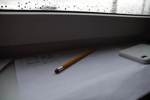 Pencil lying on scribbled paper on the windowsill on a rainy day. on the glas Stock Photos