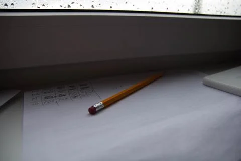 Pencil lying on scribbled paper on the windowsill on a rainy day. on the glas Stock Photos