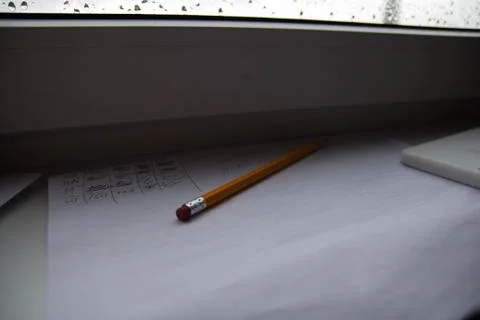 Pencil lying on scribbled paper on the windowsill on a rainy day. on the glas Foto stock
