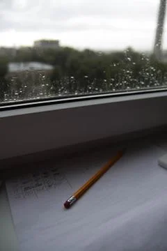 Pencil lying on scribbled paper on the windowsill on a rainy day. on the glas Stock Photos
