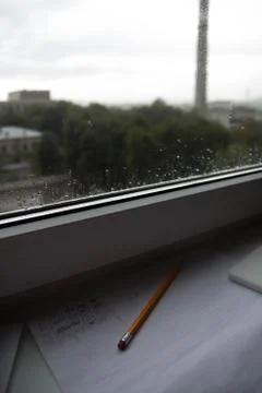 Pencil lying on scribbled paper on the windowsill on a rainy day. on the glas Stock Photos