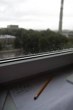 Pencil lying on scribbled paper on the windowsill on a rainy day. on the glas Stock Photos