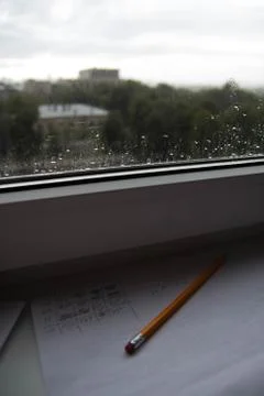 Pencil lying on scribbled paper on the windowsill on a rainy day. on the glas Stock Photos