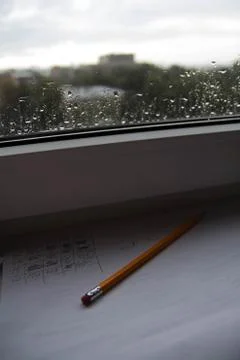 Pencil lying on scribbled paper on the windowsill on a rainy day. on the glas Stock Photos