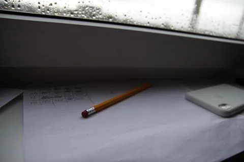 Pencil lying on scribbled paper on the windowsill on a rainy day. on the glas Stock Photos