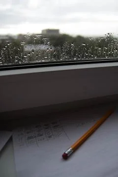 Pencil lying on scribbled paper on the windowsill on a rainy day. on the glas Stock Photos