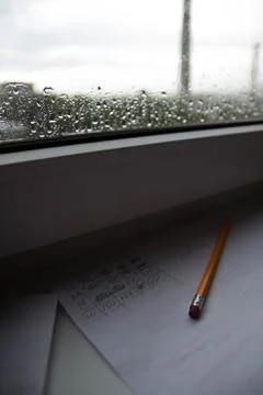Pencil lying on scribbled paper on the windowsill on a rainy day. on the glas Stock Photos