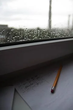 Pencil lying on scribbled paper on the windowsill on a rainy day. on the glas Stock Photos