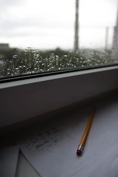Pencil lying on scribbled paper on the windowsill on a rainy day. on the glas Foto stock