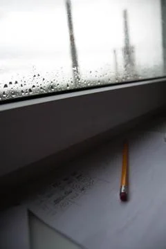 Pencil lying on scribbled paper on the windowsill on a rainy day. on the glas Stock Photos