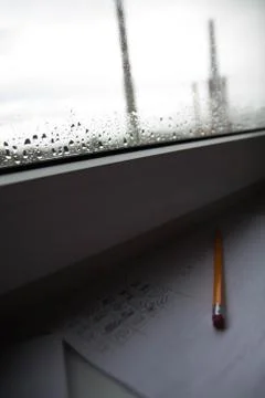 Pencil lying on scribbled paper on the windowsill on a rainy day. on the glas Stock Photos