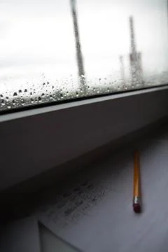 Pencil lying on scribbled paper on the windowsill on a rainy day. on the glas Stock Photos