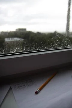 Pencil lying on scribbled paper on the windowsill on a rainy day. on the glas Stock Photos
