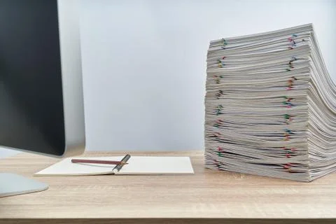 Pencil on notebook with overload paperwork and computer on table Stock Photos