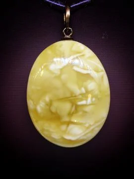 Pendant of white royal amber from the Baltic Sea on a black background close- Stock Photos