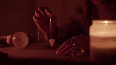 Pendulum divination during candlelit tarot session Stock Footage 306728125