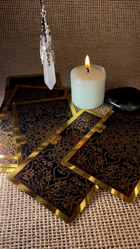 A pendulum swings gently over a burning candle and tarot cards Stock Footage 312823429