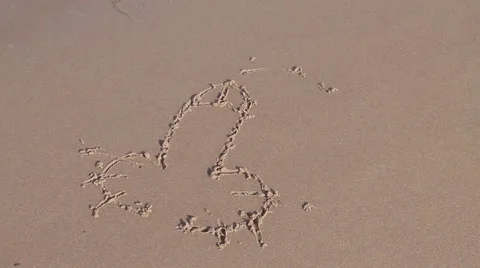 Penis shape drawn in sand washed away by wave containing sea weed Stock Footage 42741852