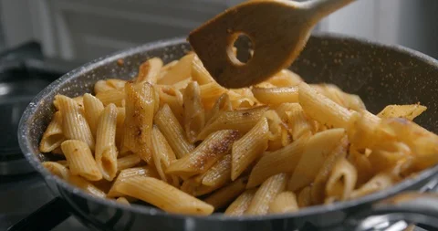 Penne pasta cooking a bit burnt slow motion 4K 動画素材 98302631