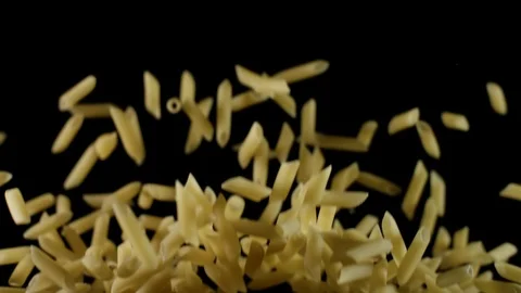 Penne pasta flies before preparation bouncing and falling down black background Stock Footage 105855617