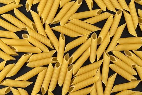 Penne rigate pasta pattern on black background, top view, flat lay texture Stock Photos