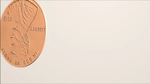 A penny tumbles onto a white surface. Stock Footage 58838721