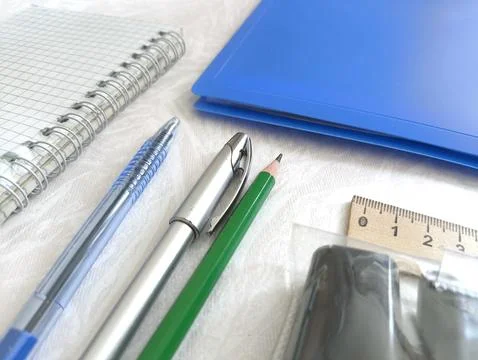 Pens, notepad, blue folder, pencils, markers, ruler on the desktop. The begin Stock Photos