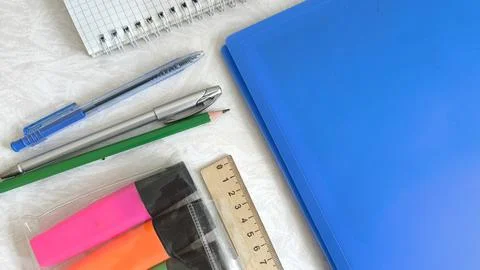Pens, notepad, blue folder, pencils, markers, ruler on the desktop. The begin Stock Photos