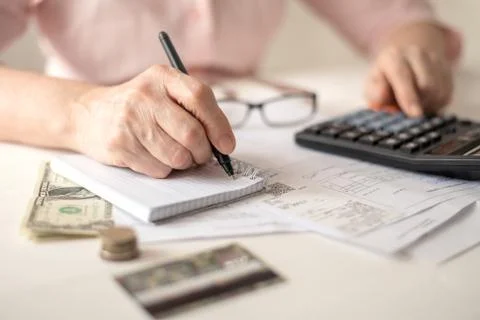 Pension calculation concept, old hands counting finances on a home calculator Stock Photos