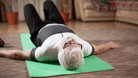 Pension man with an athletic build exercises on a mat at home Video stock 333245625