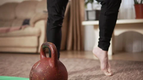 Pensioner with an athletic build doing warm-up exercises for foots in a room Video stock 333245880
