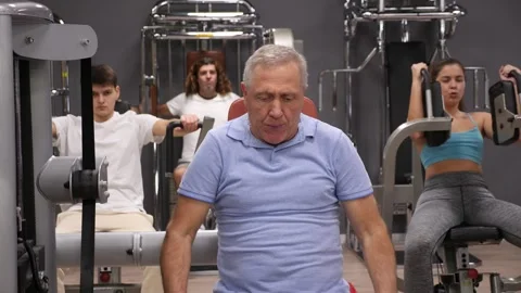 Pensioner is engaged in the simulator - develops biceps and triceps 스톡 동영상 275005313