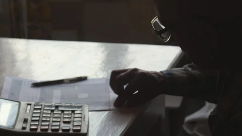 A pensioner in glasses sitting at a table with a calculator studies a finan.. Stock Footage 249041358
