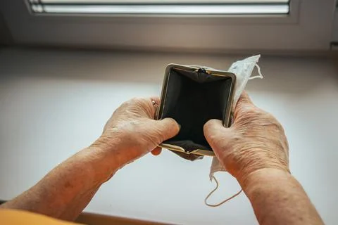 A pensioner opens a wallet. empty wallet in the hands of an elderly woman. Stock Photos