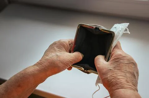 A pensioner opens a wallet. empty wallet in the hands of an elderly woman. Stock Photos