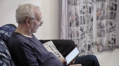 Pensioner sit on the sofa while using tablet Stock Footage 63394275