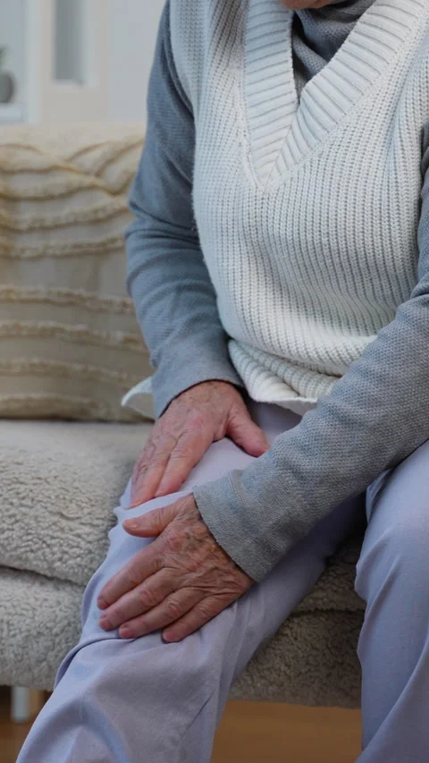 Pensioner suffering from knee pain while sitting at home Stock Footage 309061554