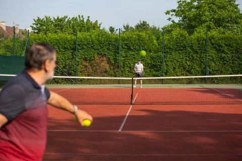 Pensioners playing tennis, seniors enjoying leisure tennis outside, lifestyle Stock Photos