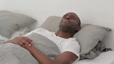 Pensive African Man Lying in Bed Stock Footage 287901387