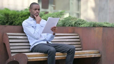 Pensive African Man Thinking while Reading Documents, Outdoor Stock Footage 136031947